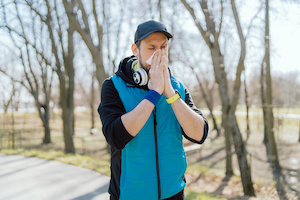 En man som är ute på en löparrunda som torkar sin näsa på grund av pollenallergi